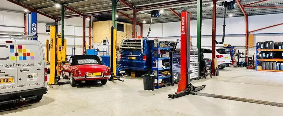 Station Road Garage workshop interior with several vehicle lifts, multiple cars being serviced, tyre storage and a clean, spacious garage environment.