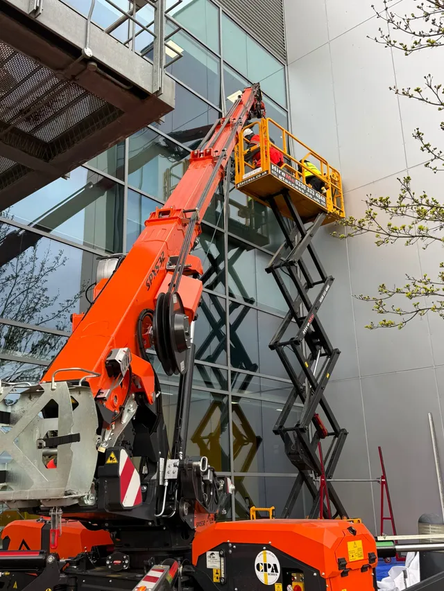 High-level glazing specialists working on commercial glass access equipment Sky Access UK working from a scissor lift and spider crane on high-level glazing at a commercial building.