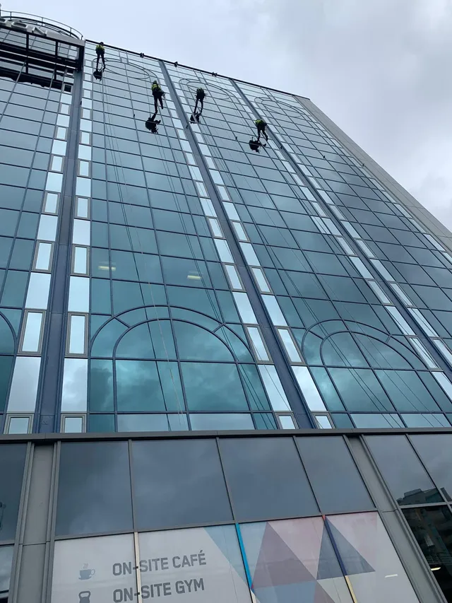 Workmen using rope systems on glass building