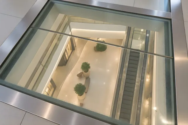 Atrium Glazing Viewed from Above View down through metal-framed atrium glazing to an interior with escalators, seating and potted trees