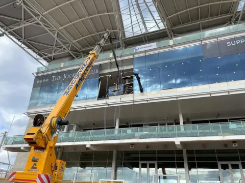 High-level commercial glass replacement at The Jockey Club by Sky Access UK Ainscough crane lifting replacement glazing at height for Sky Access UK at The Jockey Club.