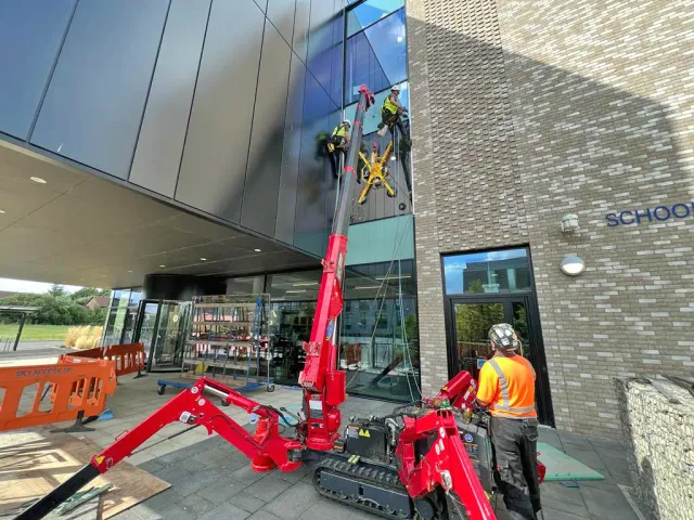 Commercial Window Repair at School Building Rope access technicians using a compact crane and glass lifting equipment to carry out high-level commercial window repair on a modern school building