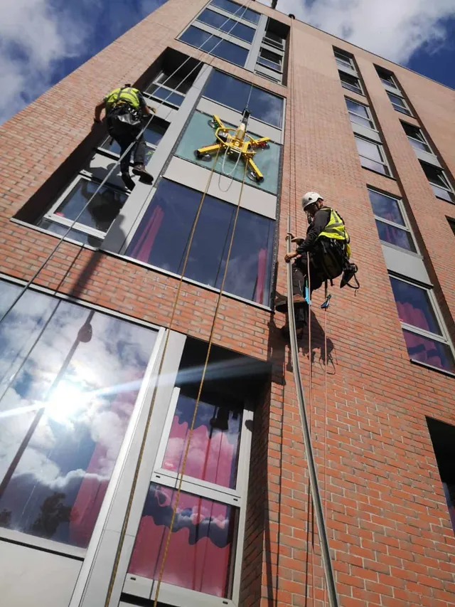 Repairing commercial windows using ropes to access high glass