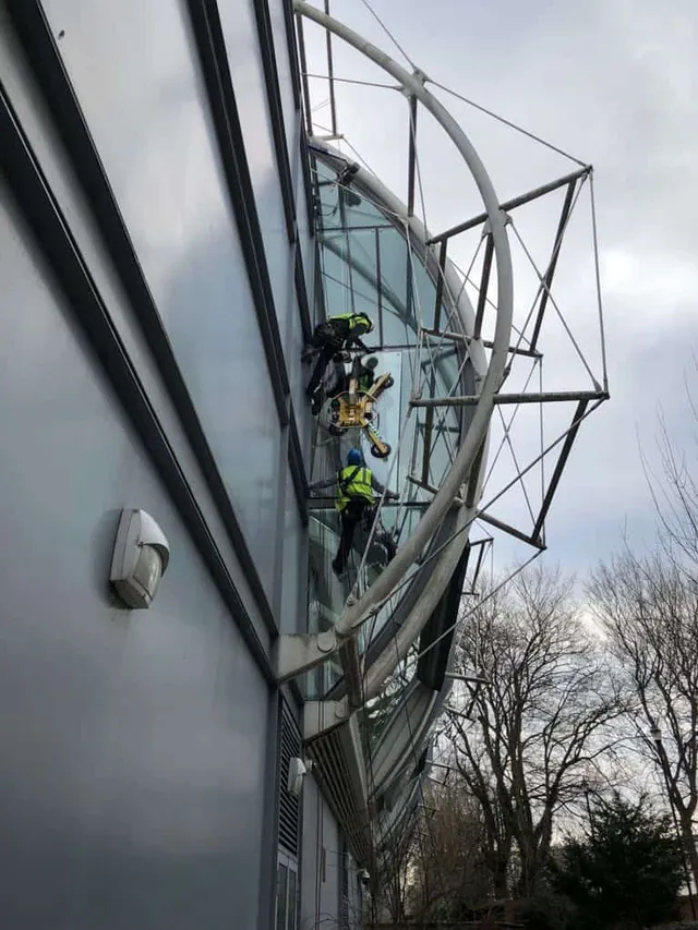 Workmen accessing difficult area to replace glass