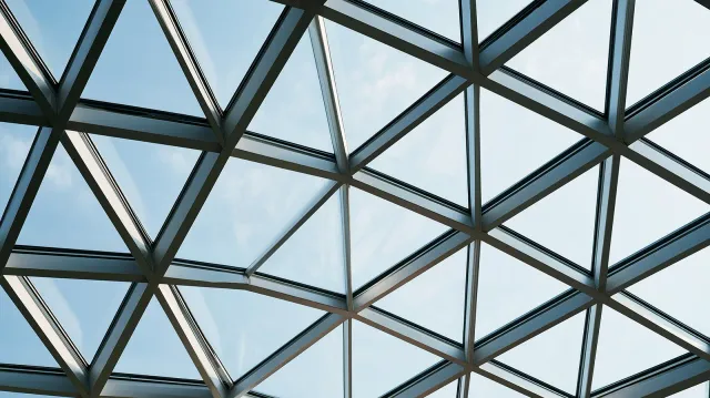 Glazed Atrium Roof with Triangular Panels View from below of a glazed atrium roof with triangular glass panels and metal framing against a blue sky