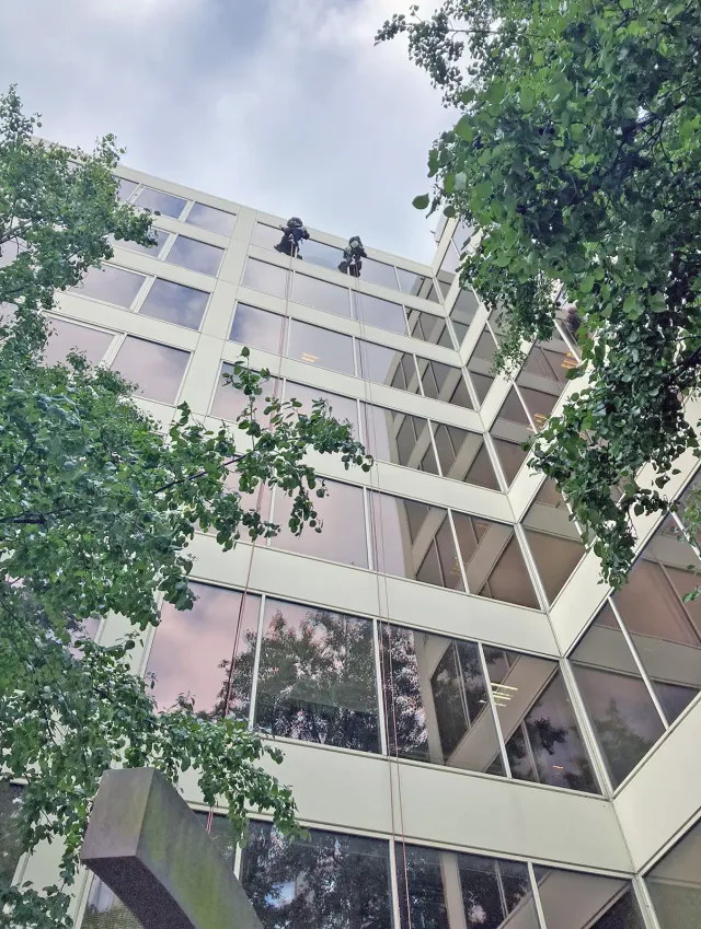 Rope Access Glazing Work on Multi-Storey Office Building Two rope access technicians working from the roof of a multi-storey office building to carry out high-level glazing maintenance on the glass façade.