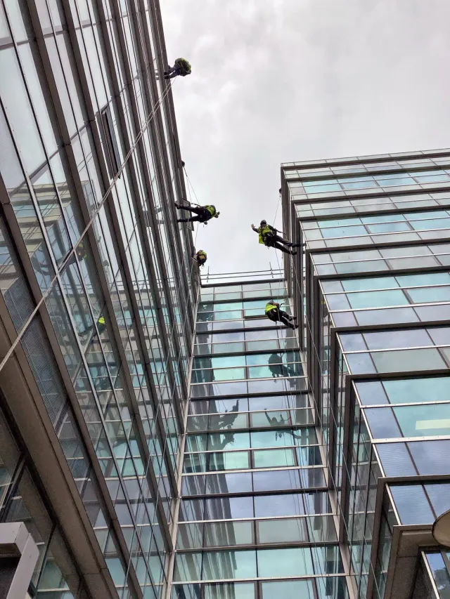 Rope Access Technicians Working on High-Rise Glass Building Multiple rope access technicians carrying out high-level maintenance work on the glass façade of a multi-storey commercial building.