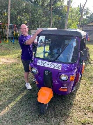 Sky Access Glazing EACH Tuk Tuk Challenge in Sri Lanka Sky Access Glazing team member standing beside a purple tuk tuk in Sri Lanka during the EACH charity Tuk Tuk Challenge.